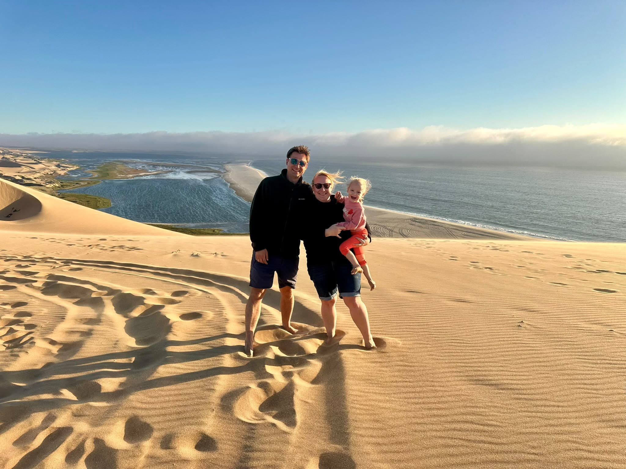 Die Familie hinter Flanea gemeinsam auf einer Sanddüne am Meer